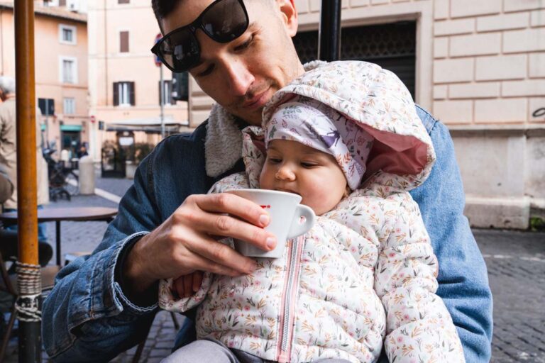 Man with baby tasting cappuccino and roman food in Rome